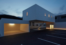 东京附近的一家牙科诊所和车库的平坦屋顶上平衡了一座白色小房子